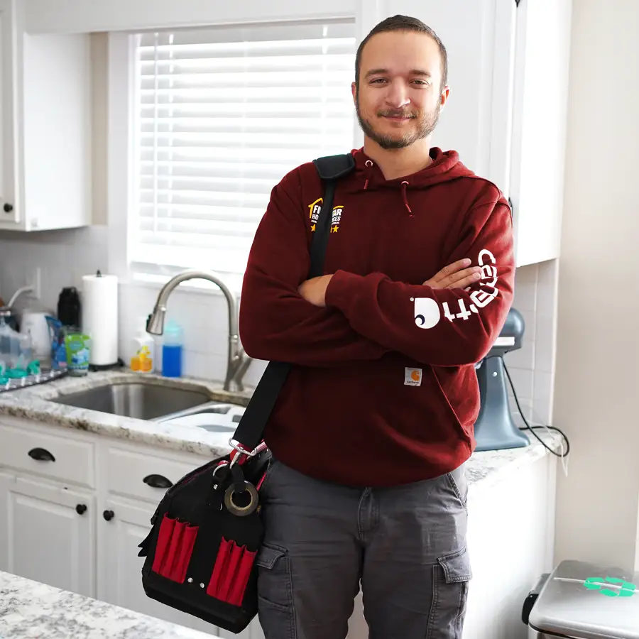 Plumber with tools standing in front of a kitchen sink