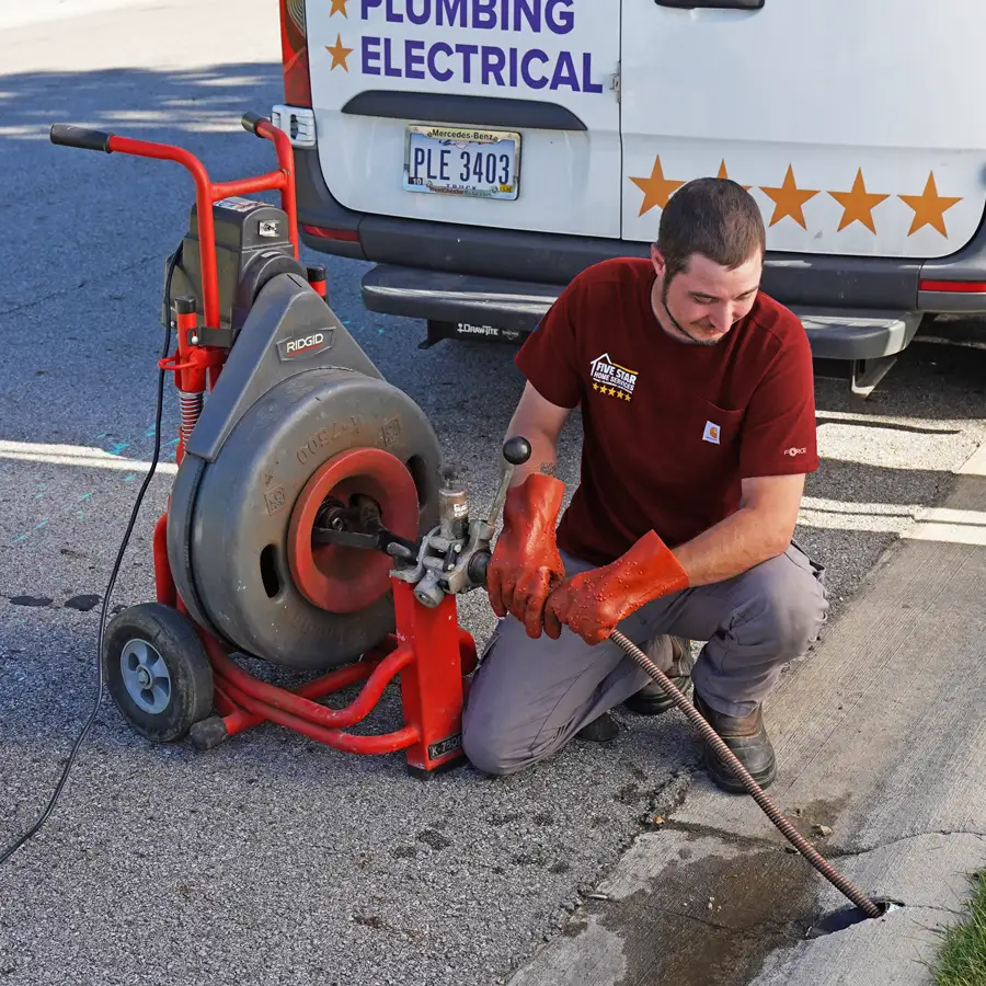 plumber kneeling with equipment by a sewer