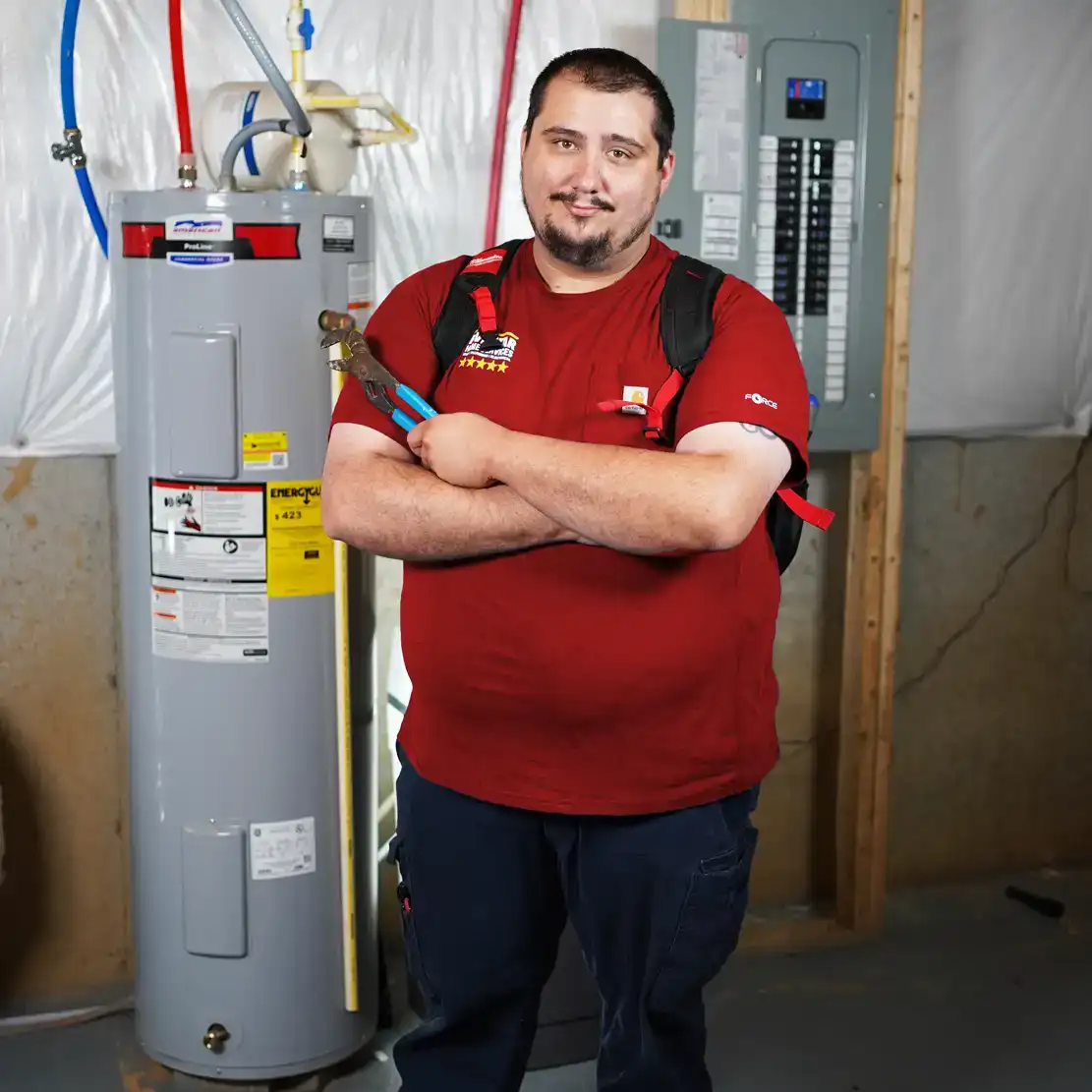 Plumber standing next to a water heater holding a wrench