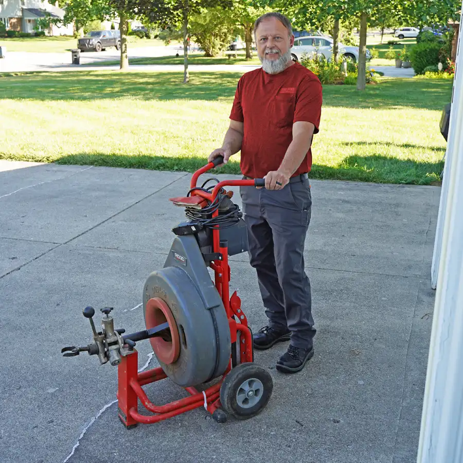 Plumber standing next to video camera inspection equipment on a driveway