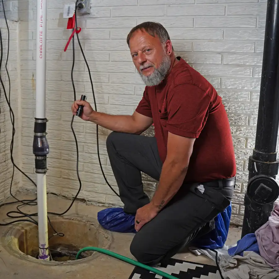 Plumbing holding a flashlight inspecting a sump pump