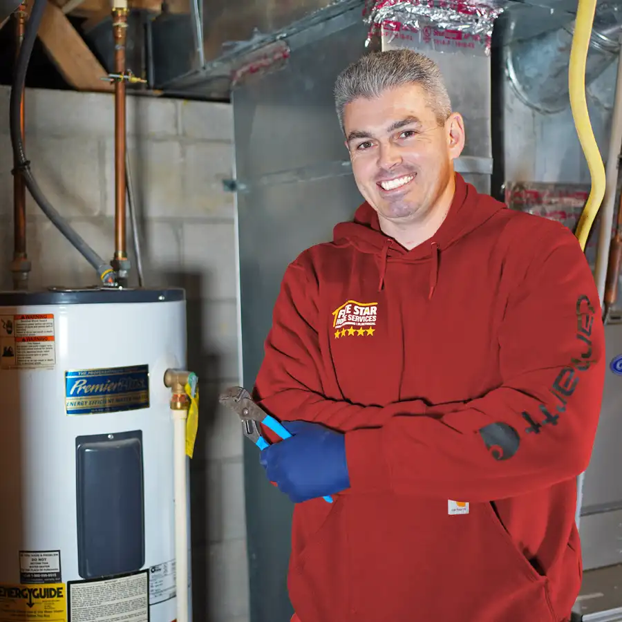 Plumber holding a wrench next to a water heater