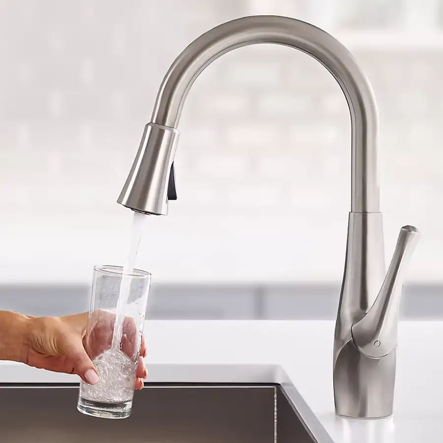 Close up of a hand holding a cup getting water from a faucet