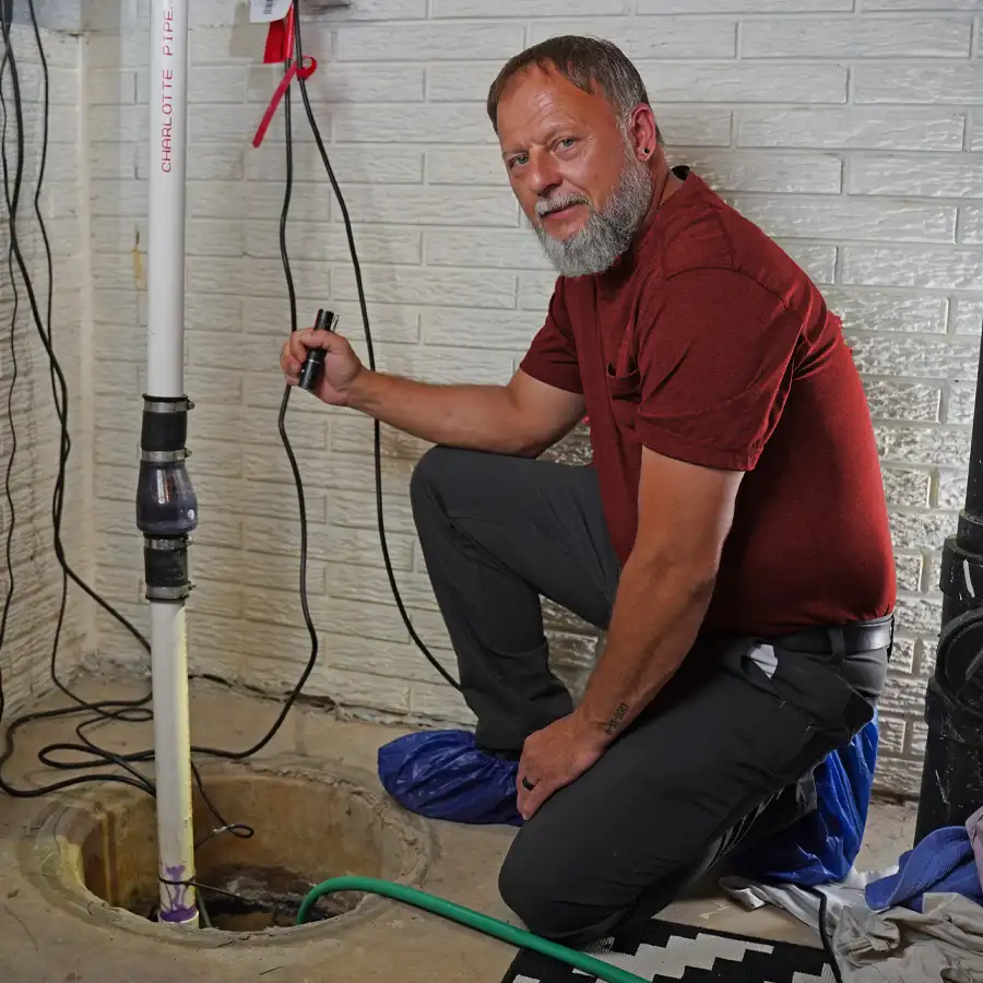 Plumber holding a flash light looking at a sump pump