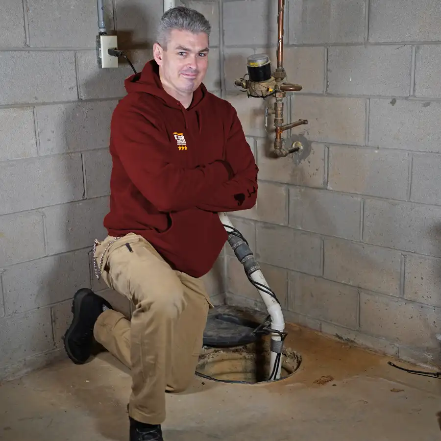 Plumber kneeling in front of a sump pump