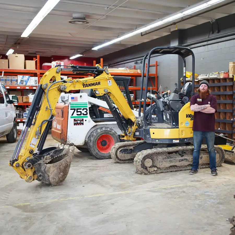 Plumber standing in front of an excavator